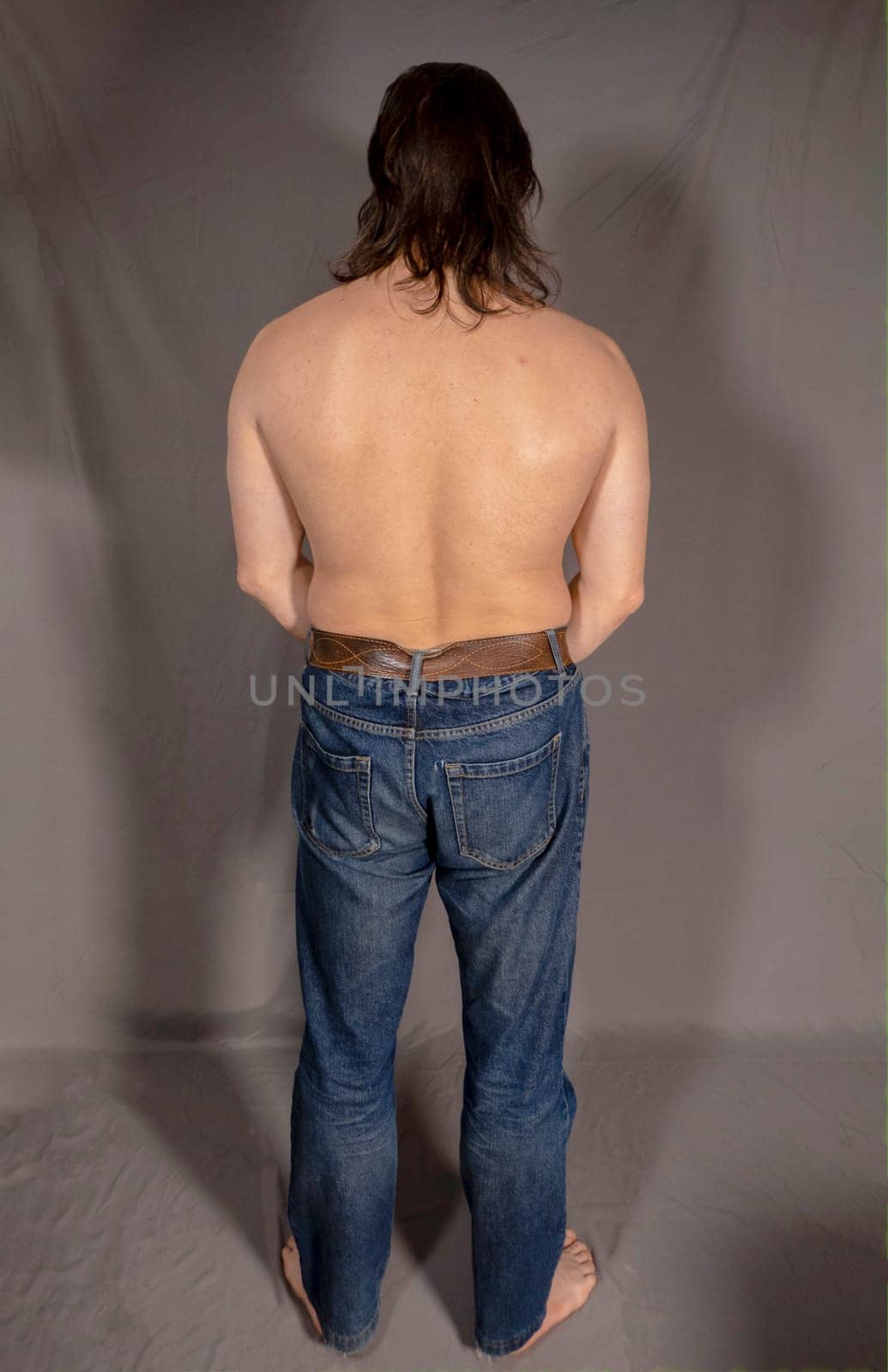 Portrait of a sexy young man with muscular body posing at studio. Gray background. Men's health. High quality photo