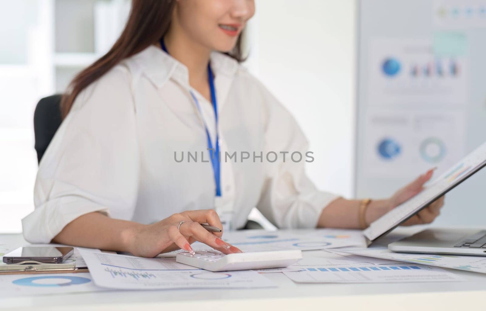 Businesswoman using calculator to do finance, mathematics on white table in office and business background, graph, tax, accounting, statistics and analytical research concept..