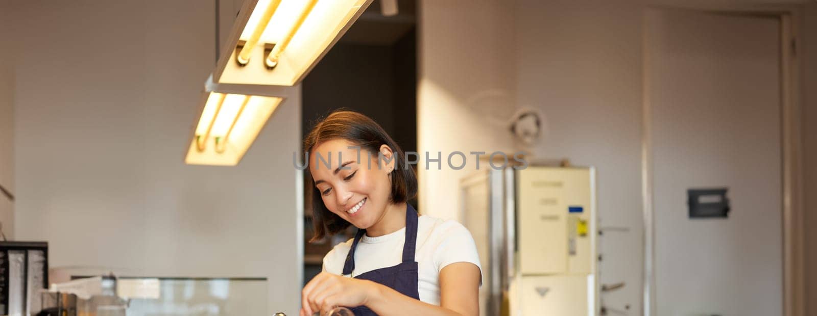 Cute korean barista girl, pouring coffee, prepare filter batch brew pour over, working in cafe. Workplace and people concept