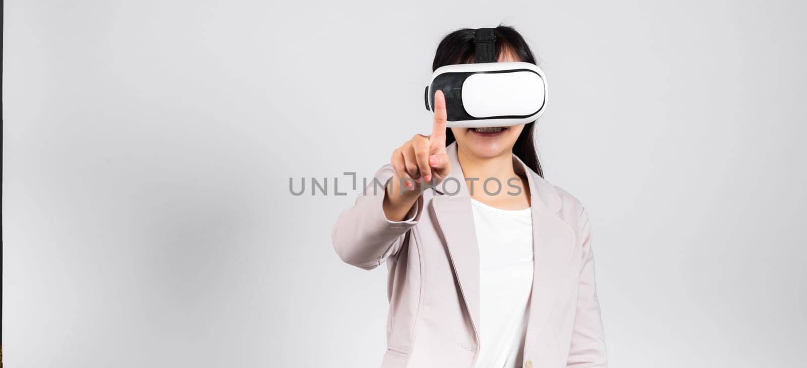 Smiling woman confidence wearing VR headset device touching air during virtual reality experience isolated white background, Asian happy portrait female playing video game studio shot, copy space