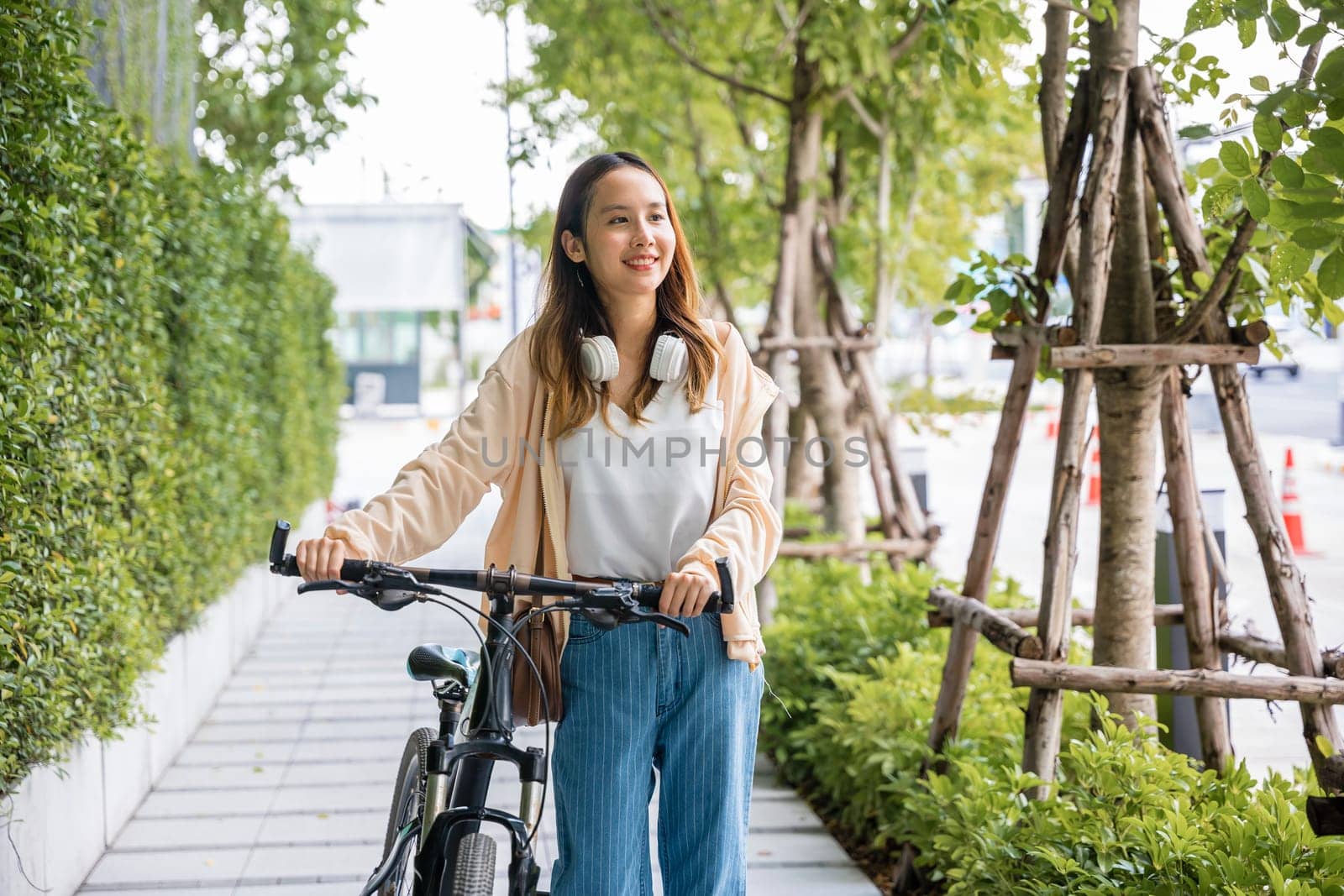 Lifestyle Asian young woman walking alongside with bicycle on summer in countryside outdoor by Sorapop