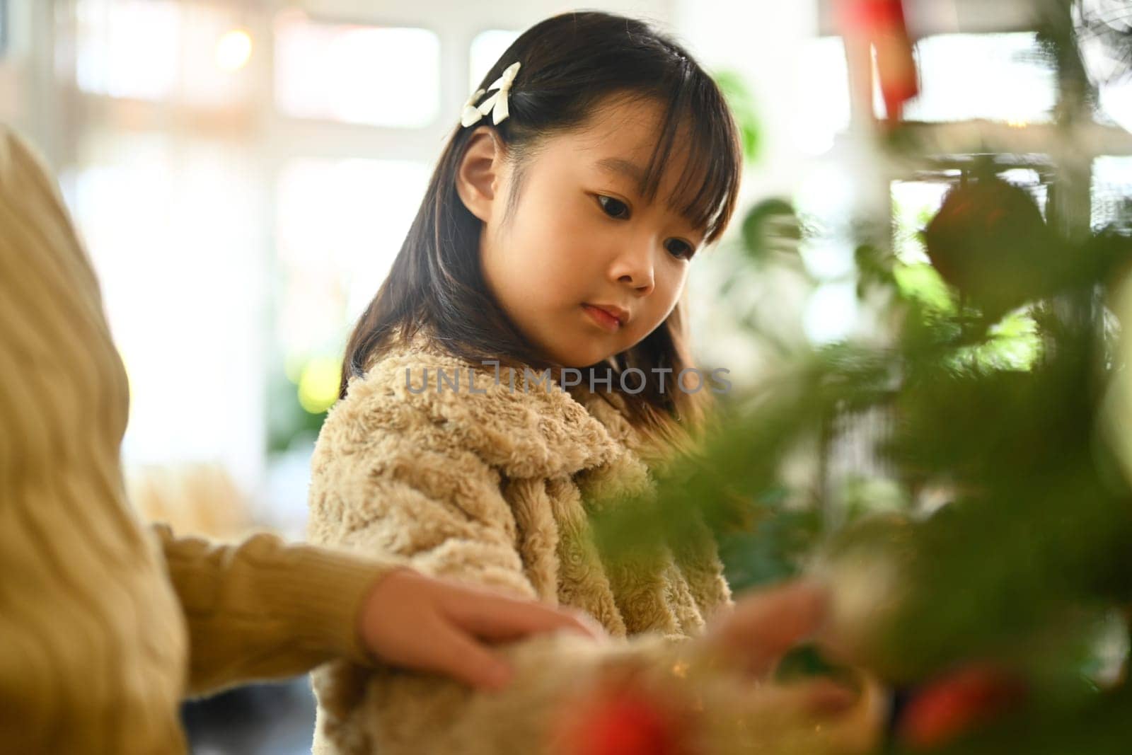Image of adorable girl decorating Christmas tree preparing for Christmas holidays and happy new year.