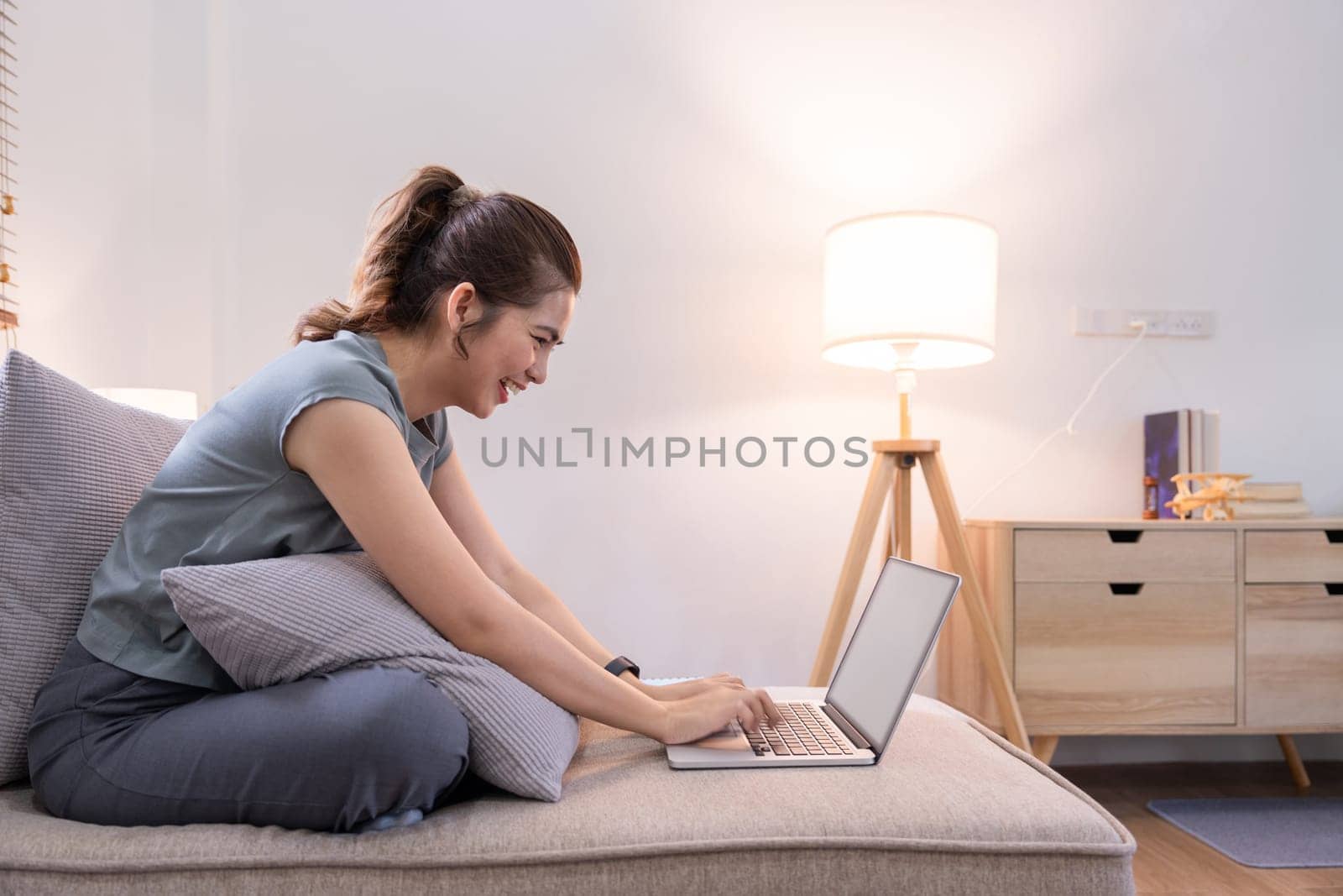 Young woman asian using laptop pc computer on couch relax surfing the net at home.