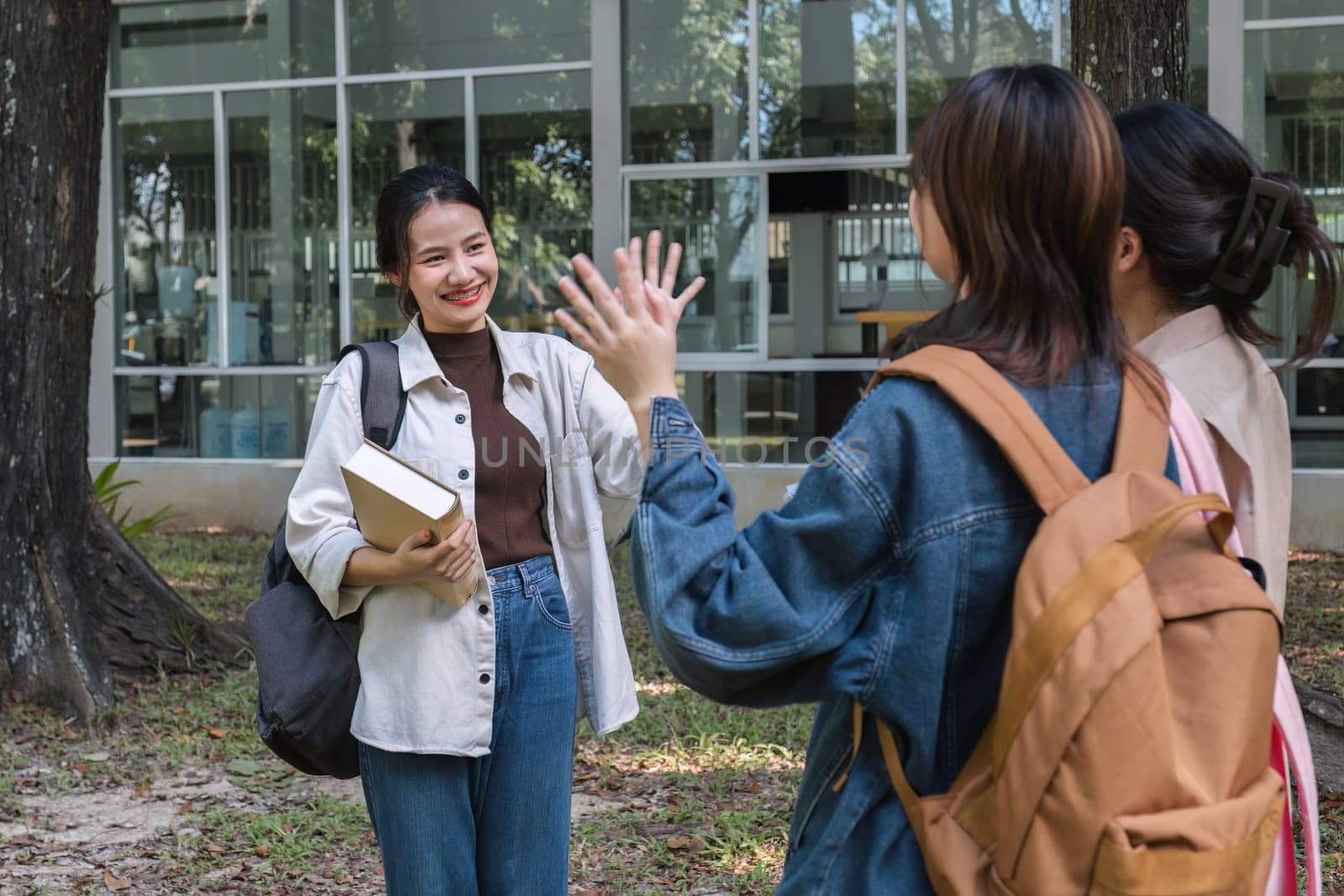 A group of cheerful Asian college students greet each other as they head to tutoring. Students greet friends on campus by wichayada