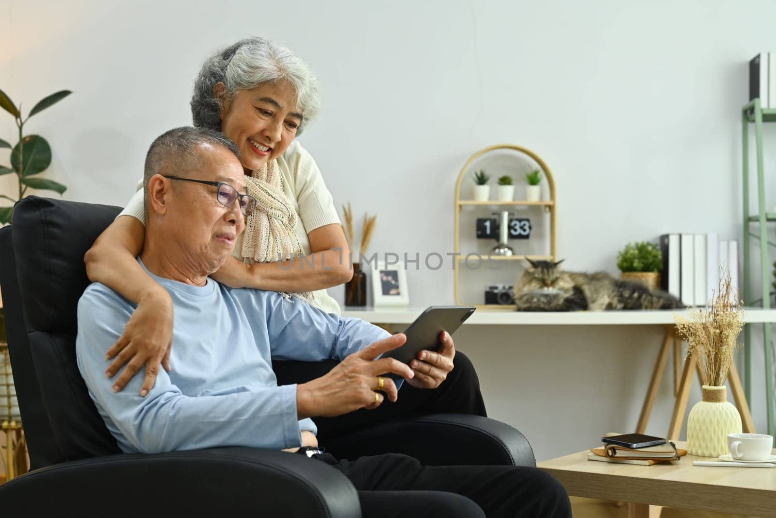 Smiling elderly woman talking to her husband in the living room. Retirement lifestyle concept.