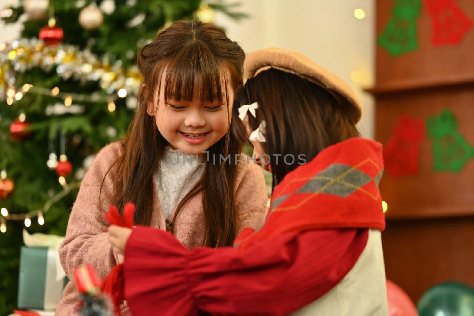 Happy smiling little girls enjoying the warm Christmas atmosphere in cozy living room.