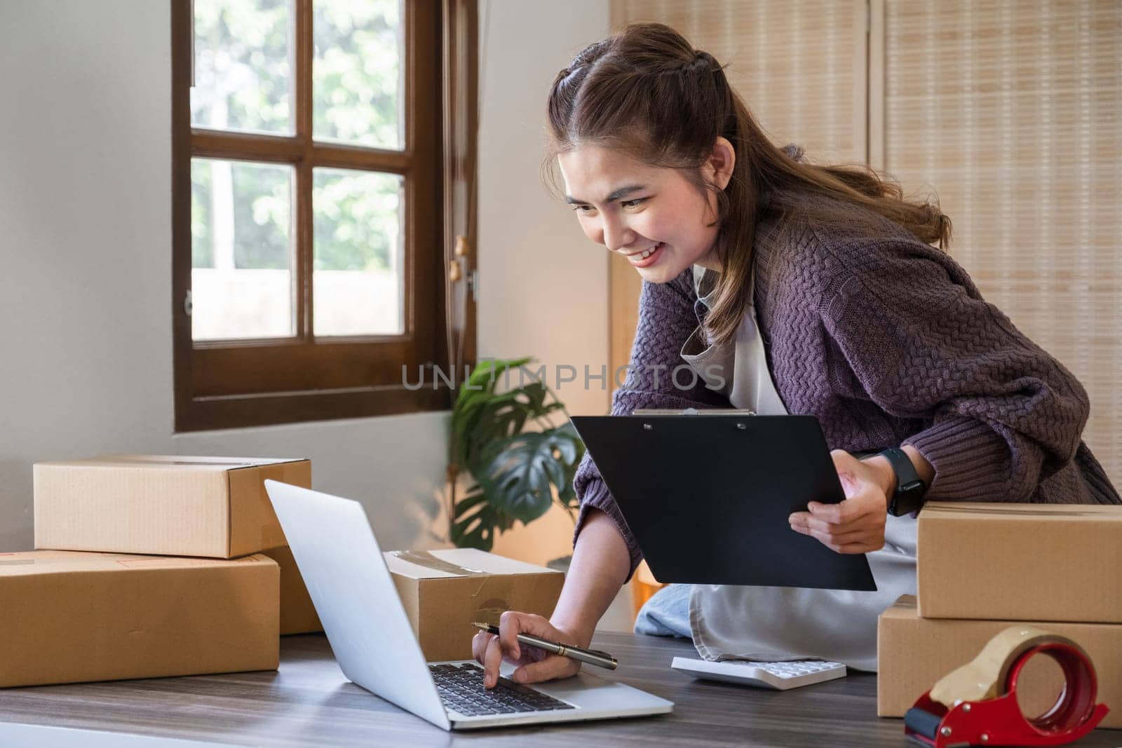 Startup small business entrepreneur SME, asian woman packing cloth in box. Portrait young Asian small business owner home office, online sell marketing delivery, SME e-commerce telemarketing concept.