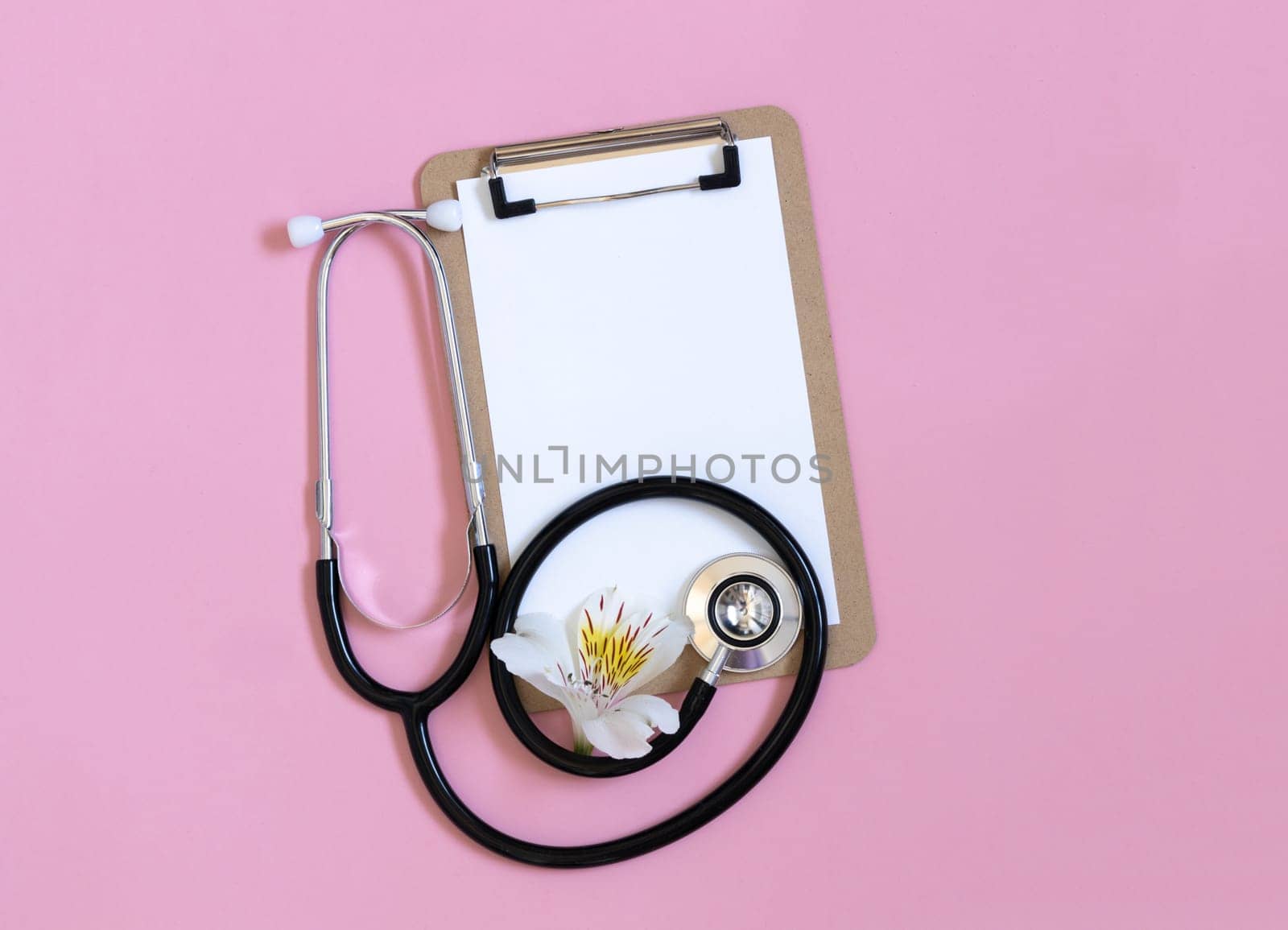 Stethoscope, white flower and empty blank for prescription on pastel pink background. by Ri6ka