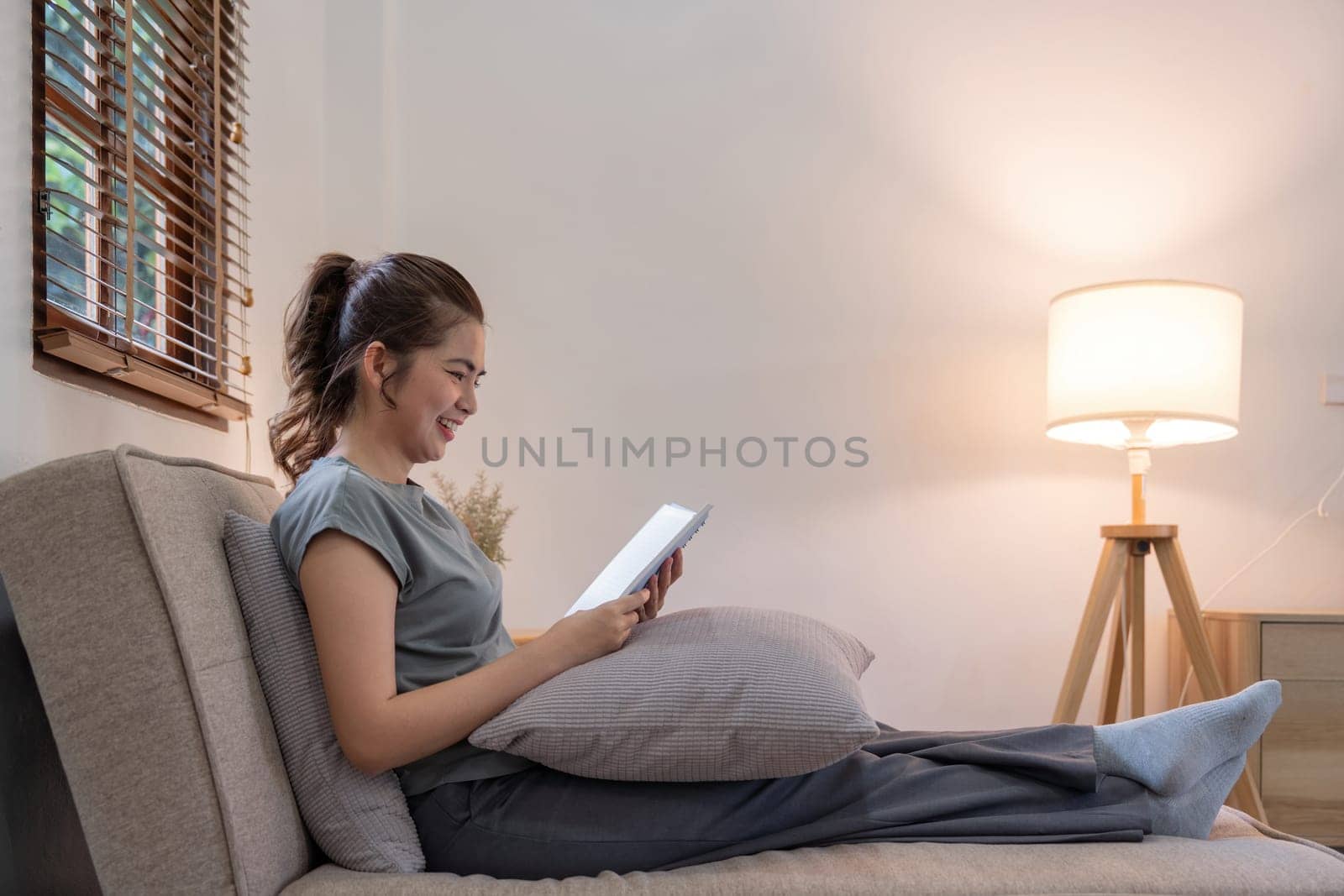 Happy young woman read book on sofa at home. Lifestyle freelance relax in living room. Lifestyle Concept.