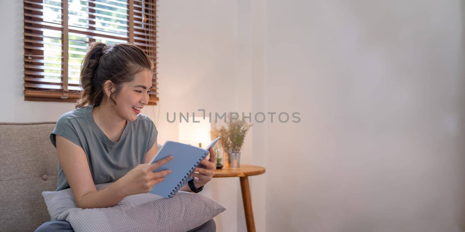 Happy young woman read book on sofa at home. Lifestyle freelance relax in living room. Lifestyle Concept.