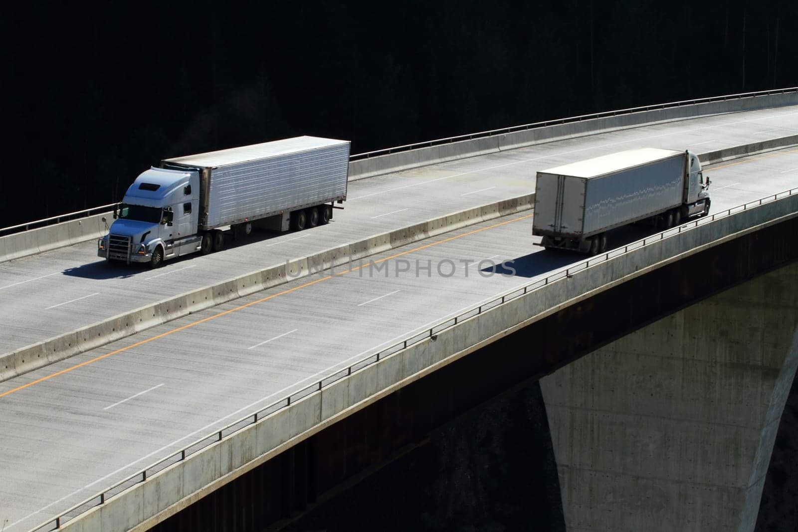 Semi-trailer trucks crossing a high level bridge in British Columbia
