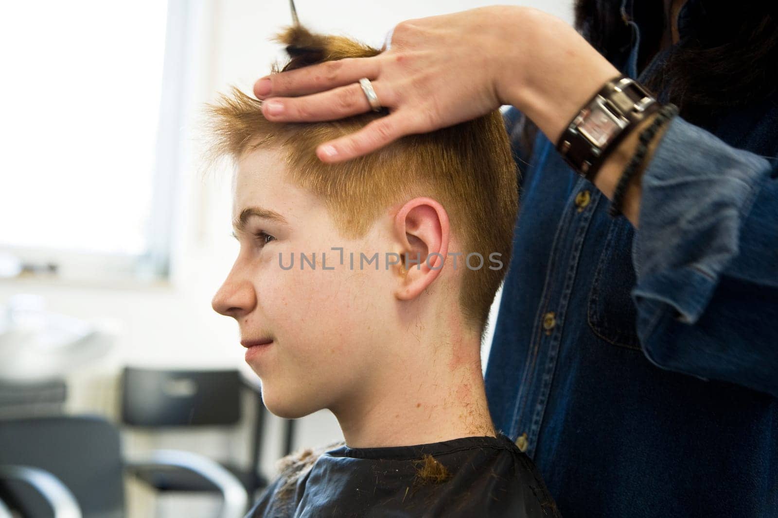 smiling young boy with red hair at the hairdresser