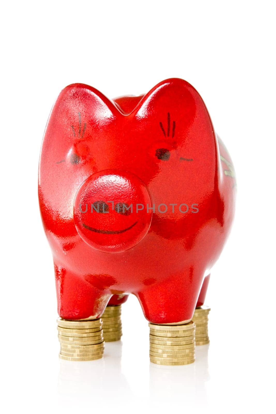 Red piggy bank standing on coins stacks