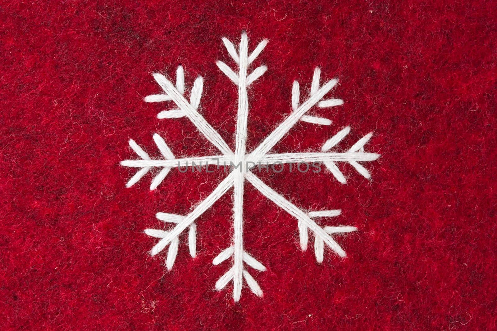 close-up of red felt with embroidered white snowflake
