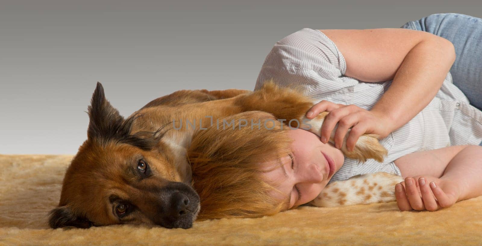 Woman lying on the floor enjoying a peaceful slumber with her head resting between the paws of her gentle protective dog