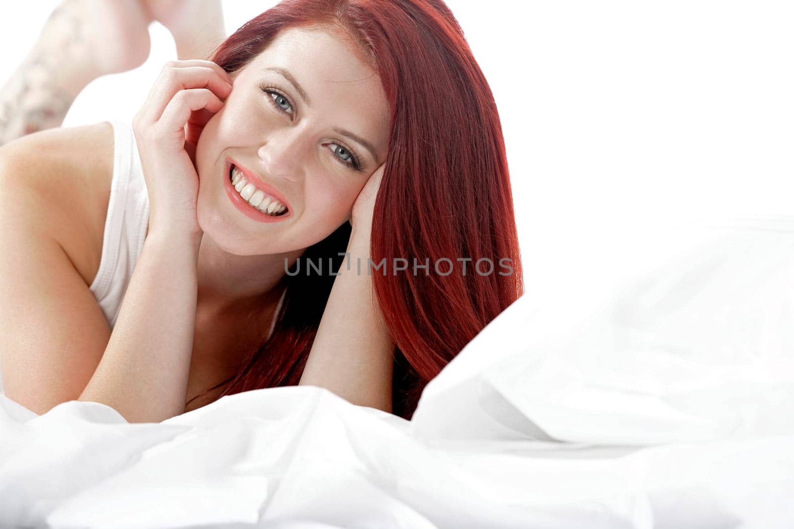 Young woman lying on her white bed at home relaxing