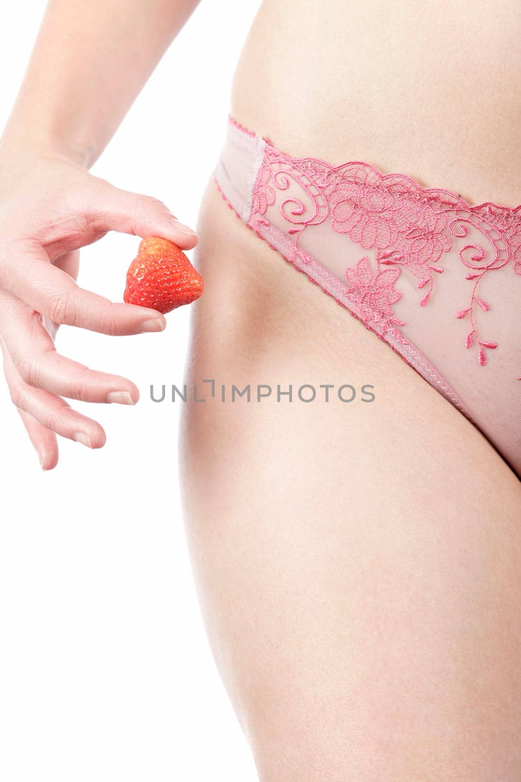 Close up of a woman's waist in underwear holding a fresh Strawberry in her right hand
