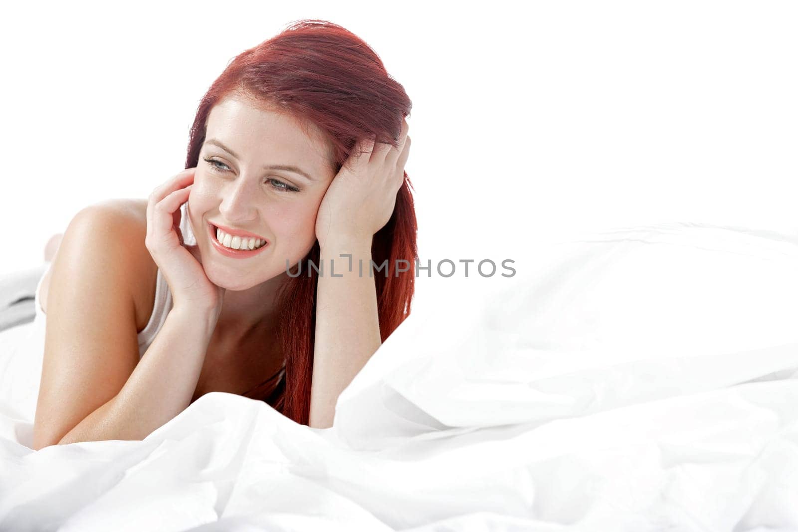 Young woman lying on her white bed at home relaxing