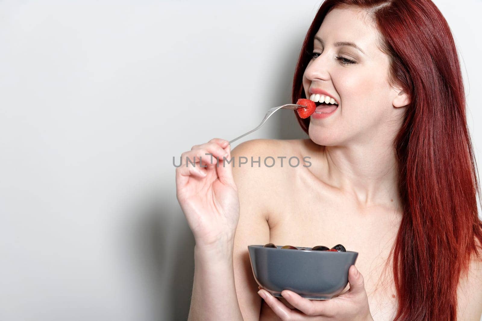 Beautiful young woman eating fresh fruit at home in her underwear