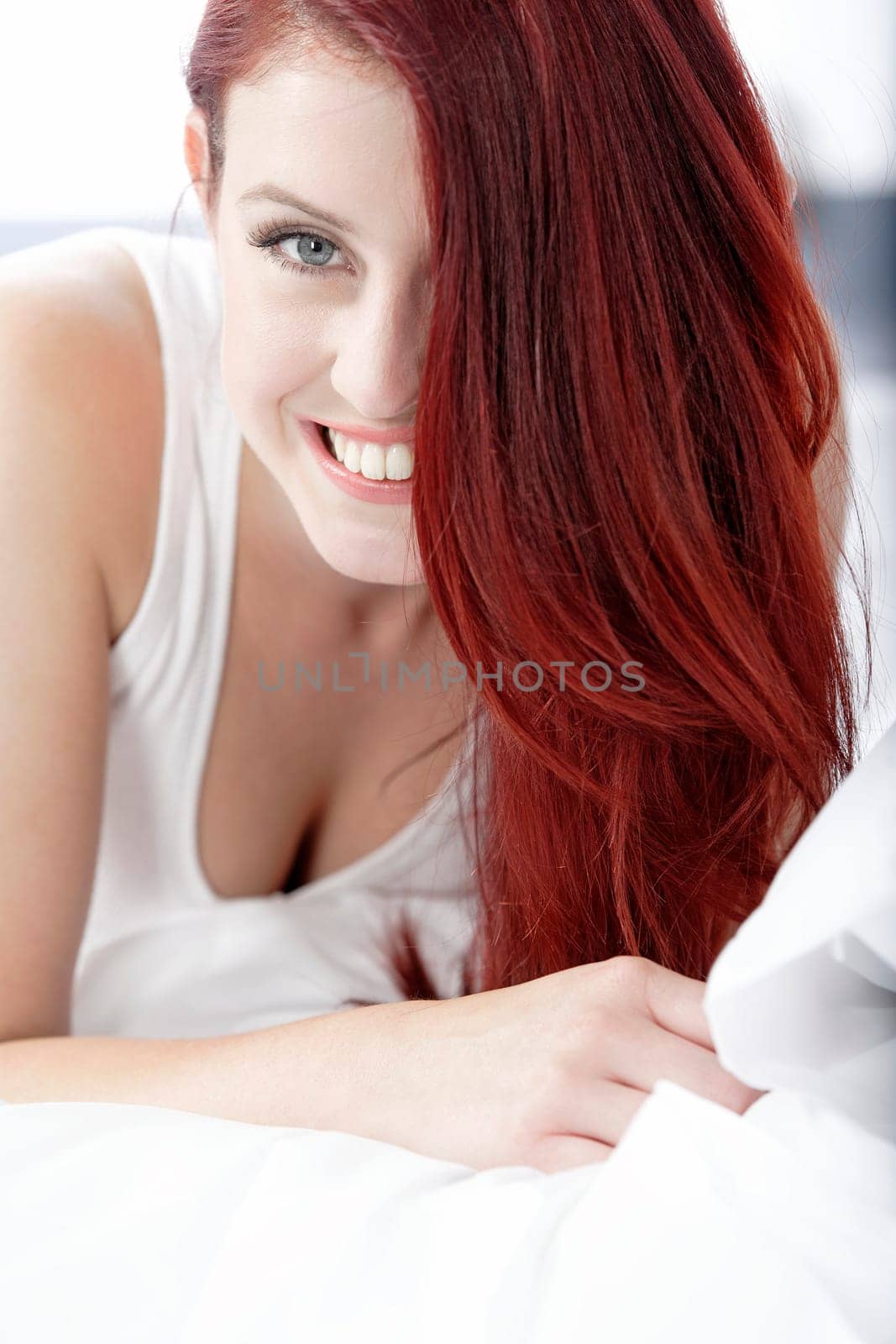 Young woman lying on her white bed at home relaxing