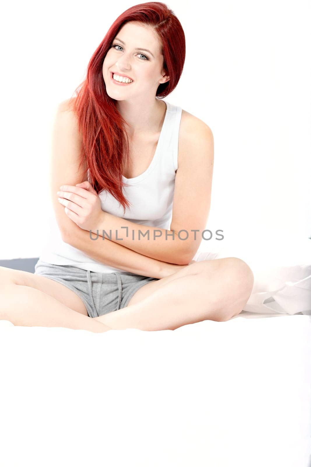 Beautiful young woman sitting on her bed at home