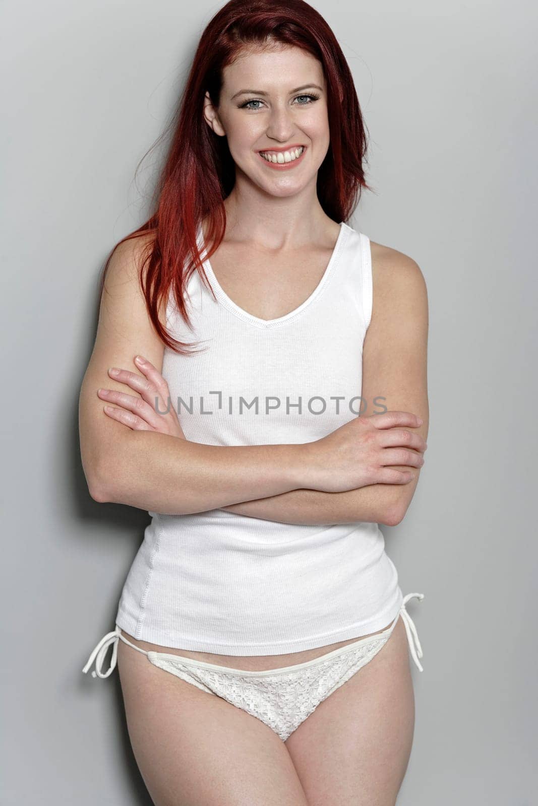 Attractive woman in white bikini bottoms and vest top posing