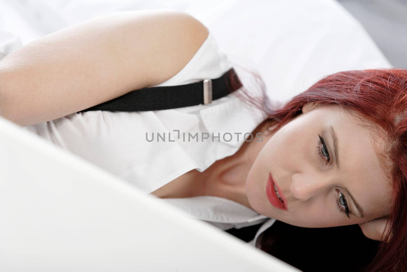 Professional business woman lying on a bed after a long day in the office still working on the laptop computer