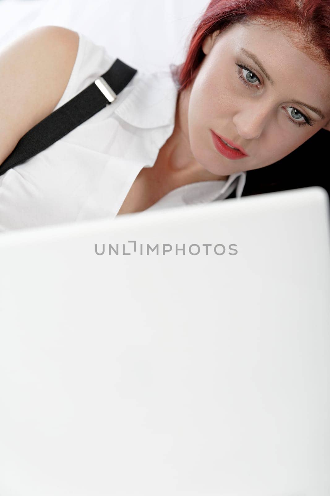 Professional business woman lying on a bed after a long day in the office still working on the laptop computer