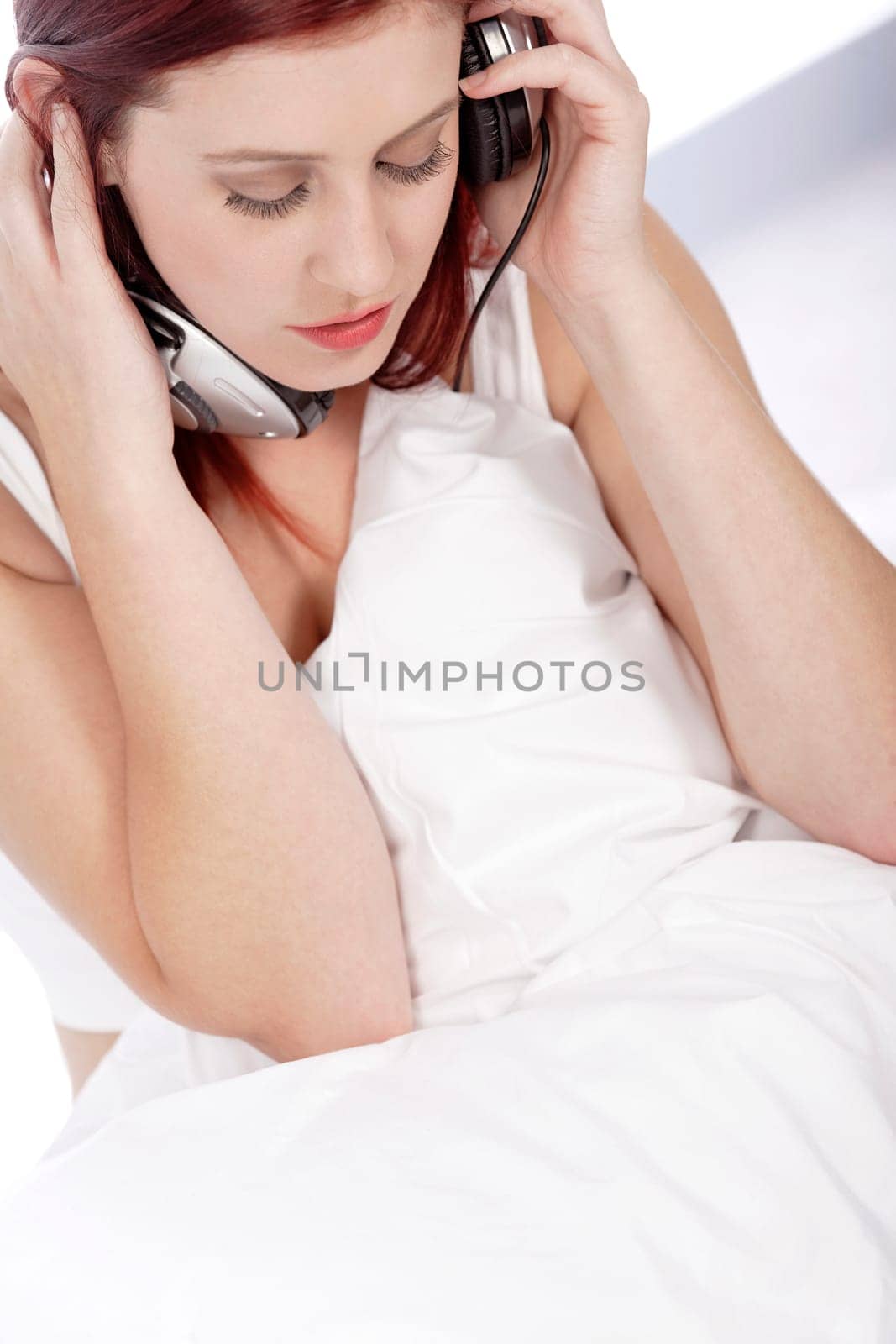Attractive young woman listening to music at home on her bed