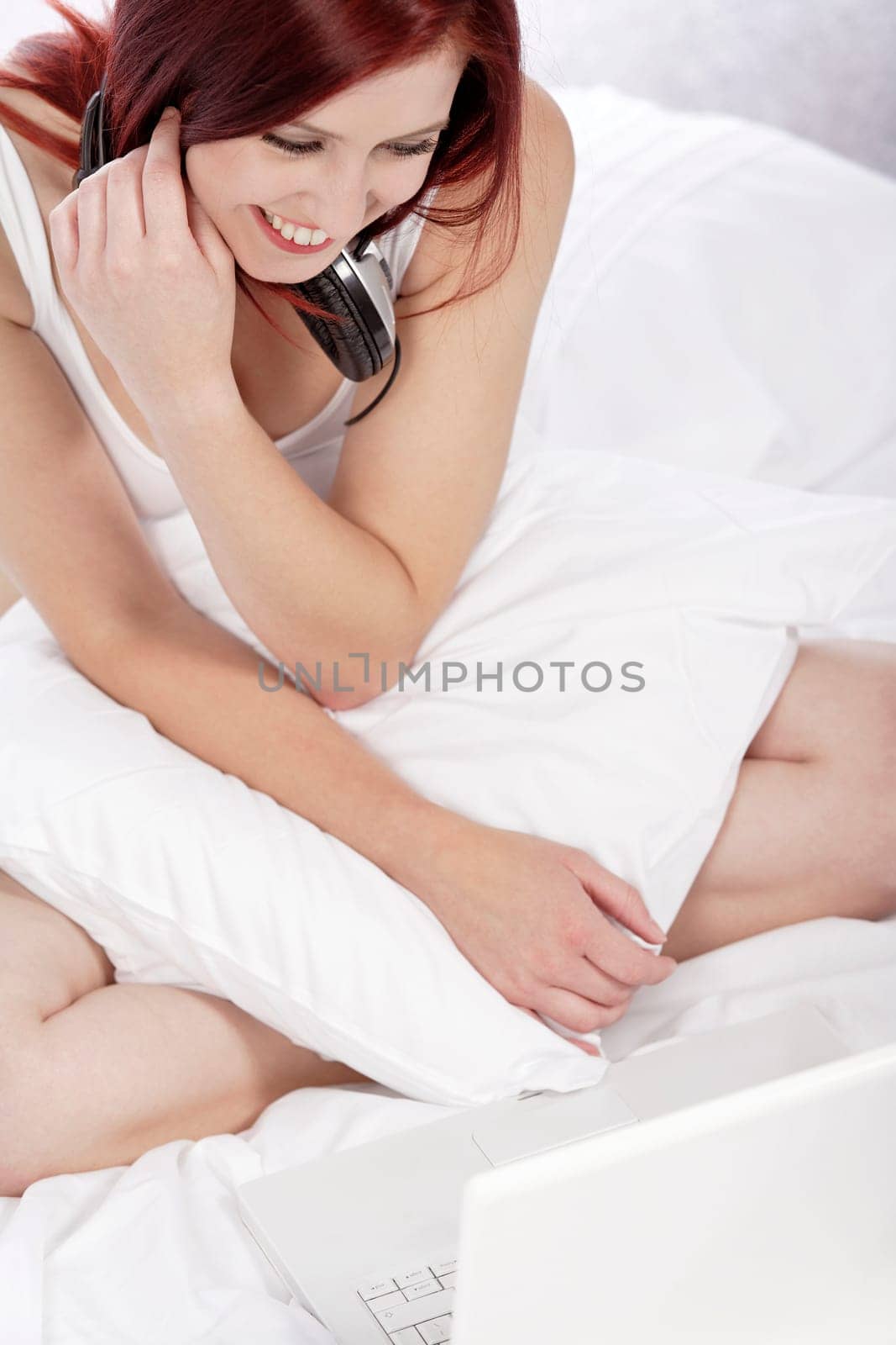 Attractive young woman listening to music at home on her bed