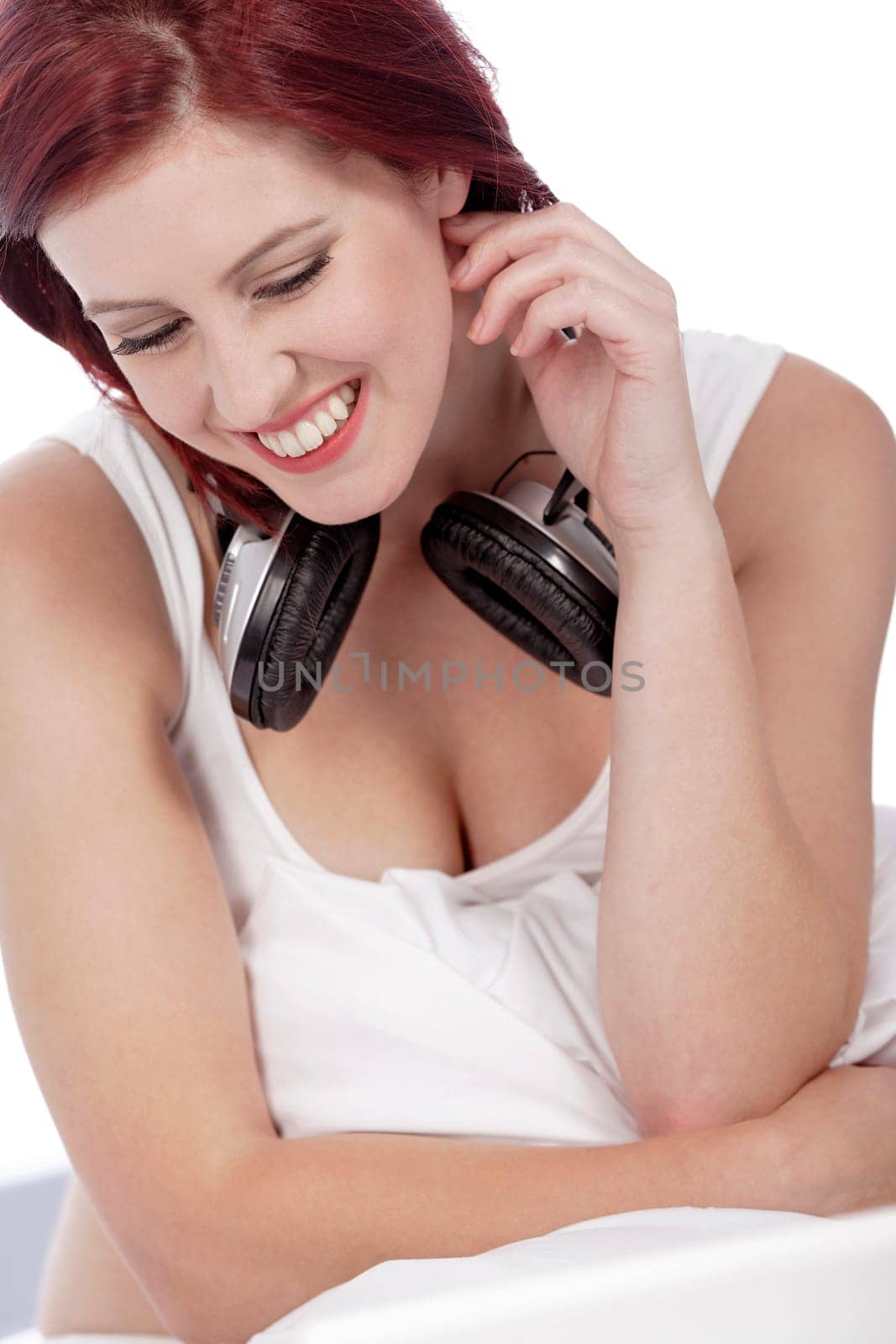 Attractive young woman listening to music at home on her bed