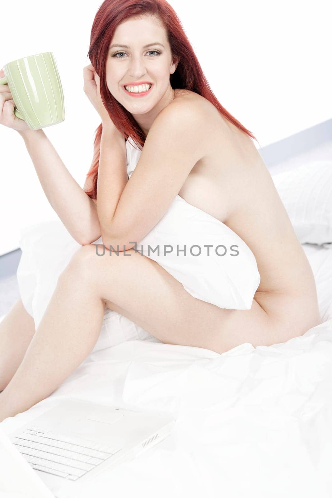 Beautiful young woman naked on her bed at home relaxing on the white covers