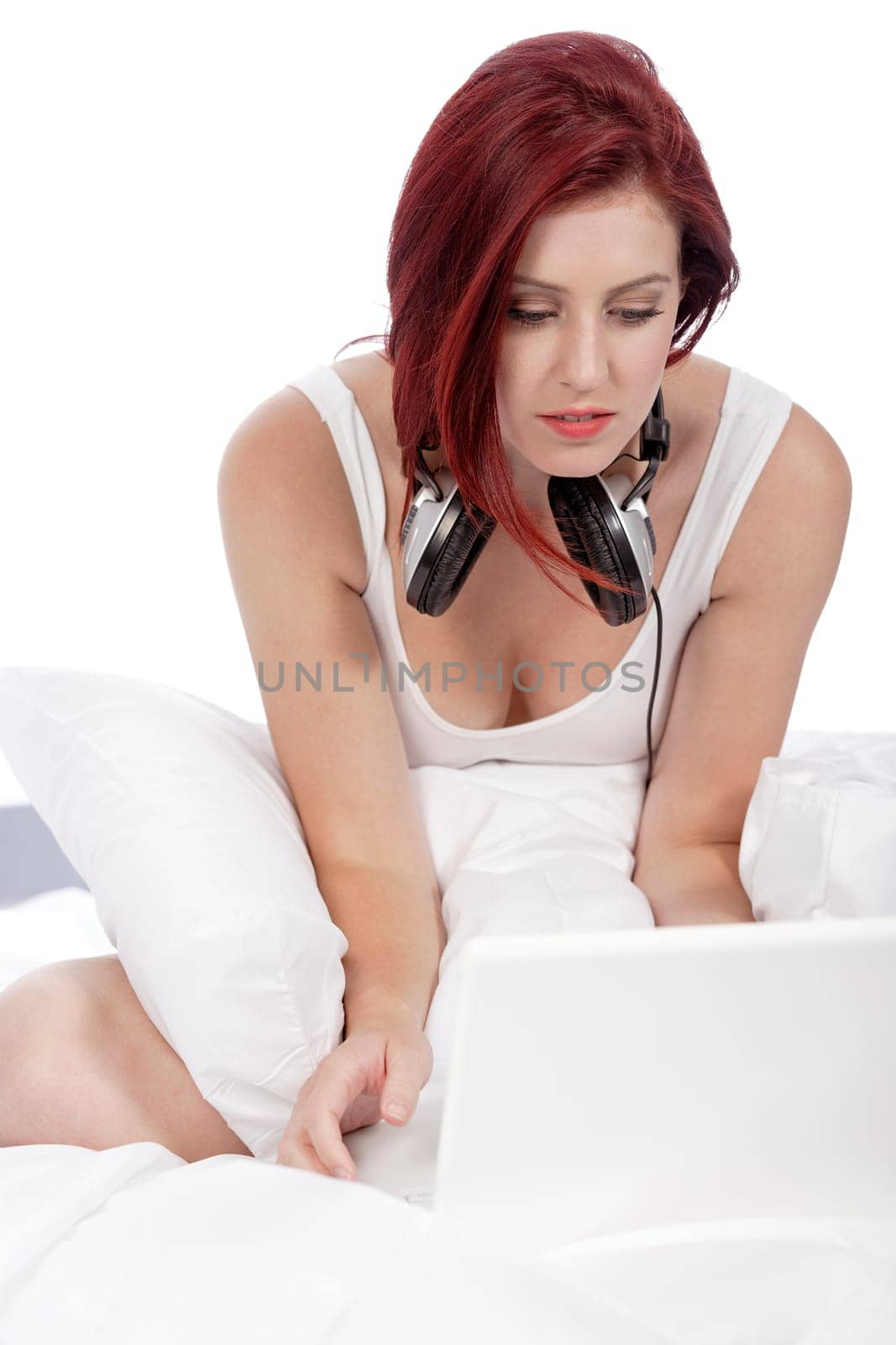 Attractive young woman listening to music at home on her bed