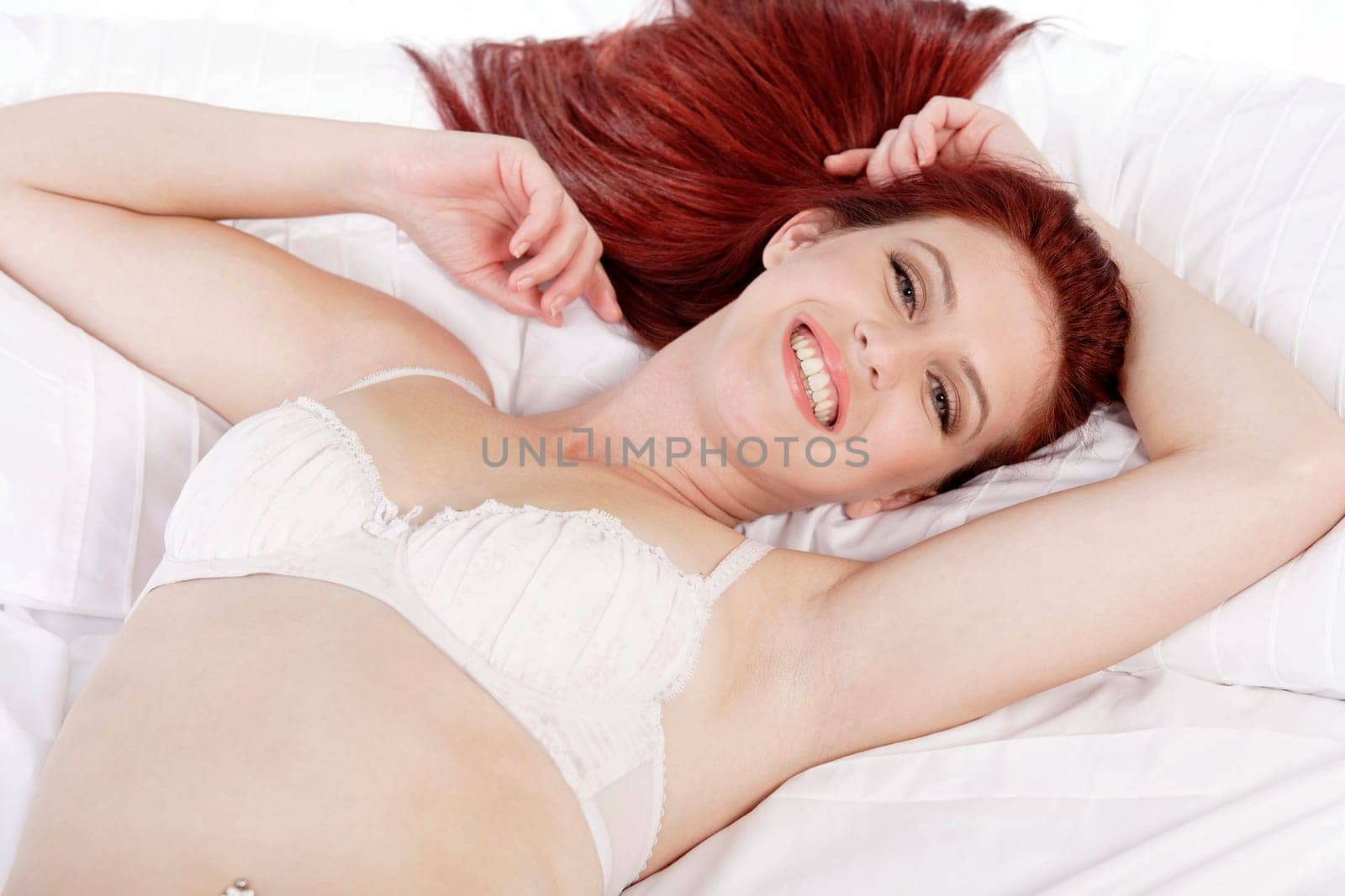 Attractive young woman lying on her bed in her underwear at home