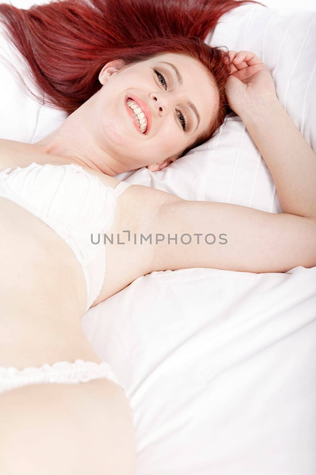 Attractive young woman lying on her bed in her underwear at home