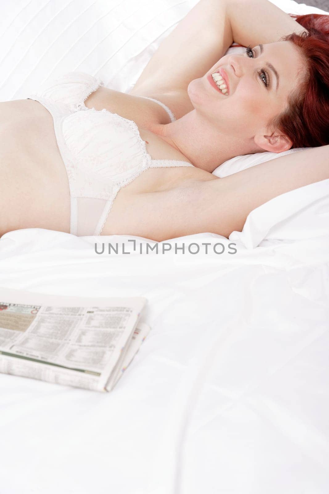 Attractive young woman lying on her bed in her underwear at home