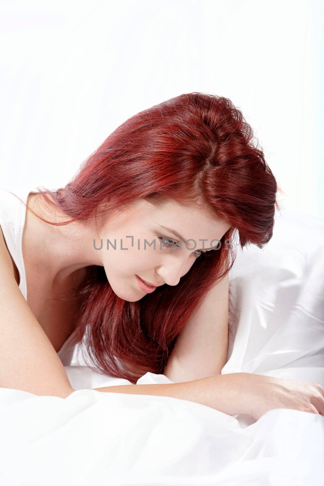 Young woman lying on her white bed at home relaxing