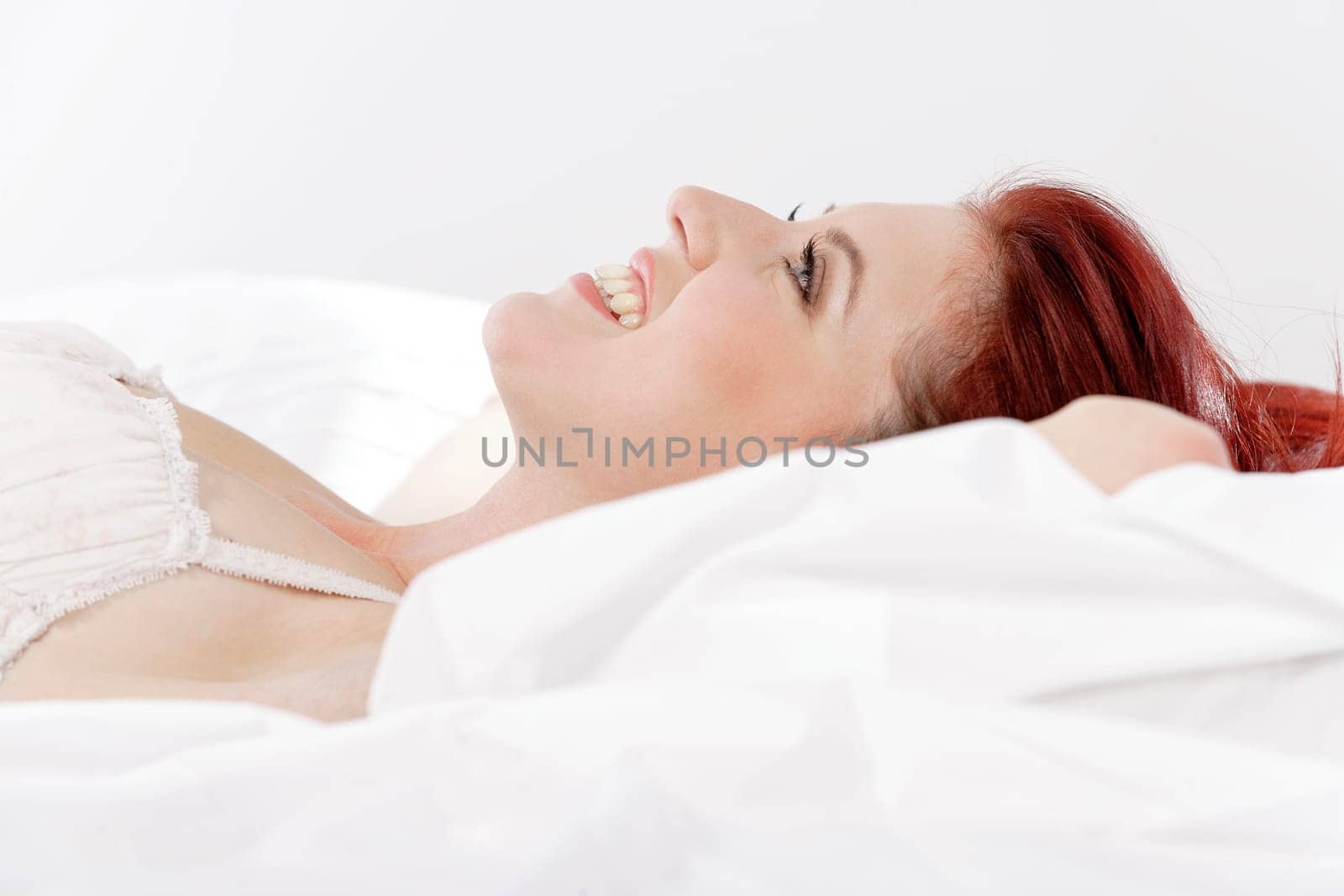 Attractive young woman lying on her bed in her underwear at home