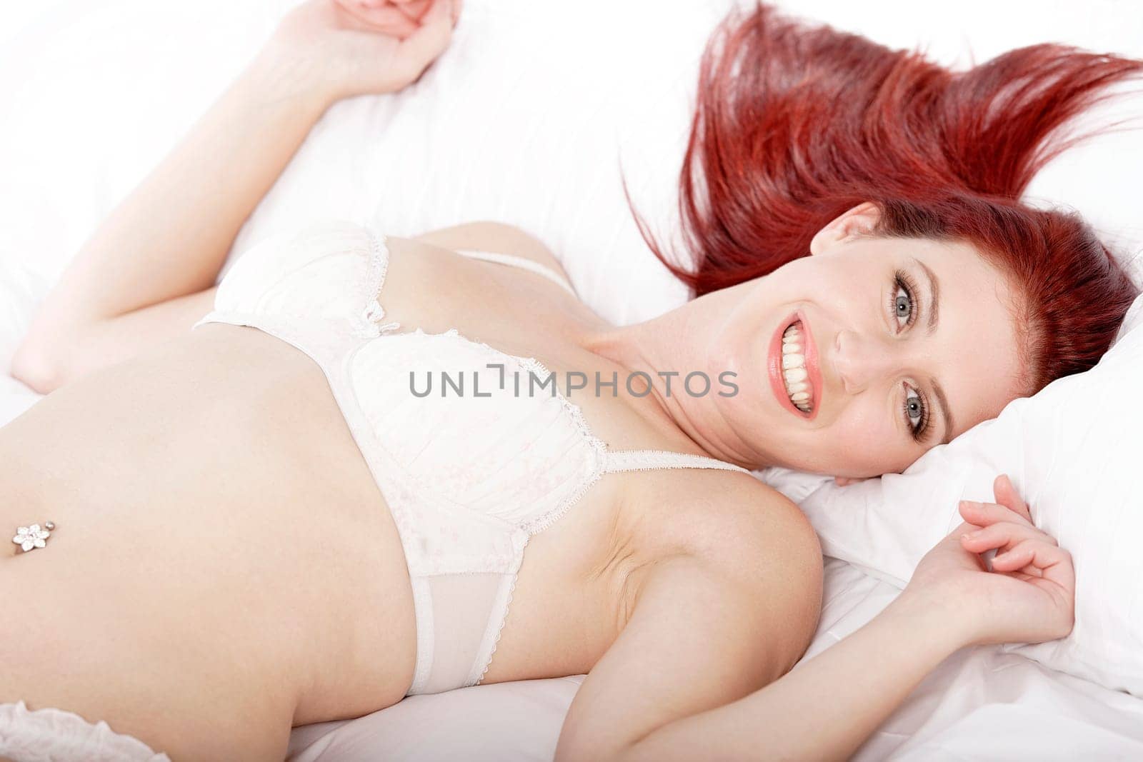 Attractive young woman lying on her bed in her underwear at home