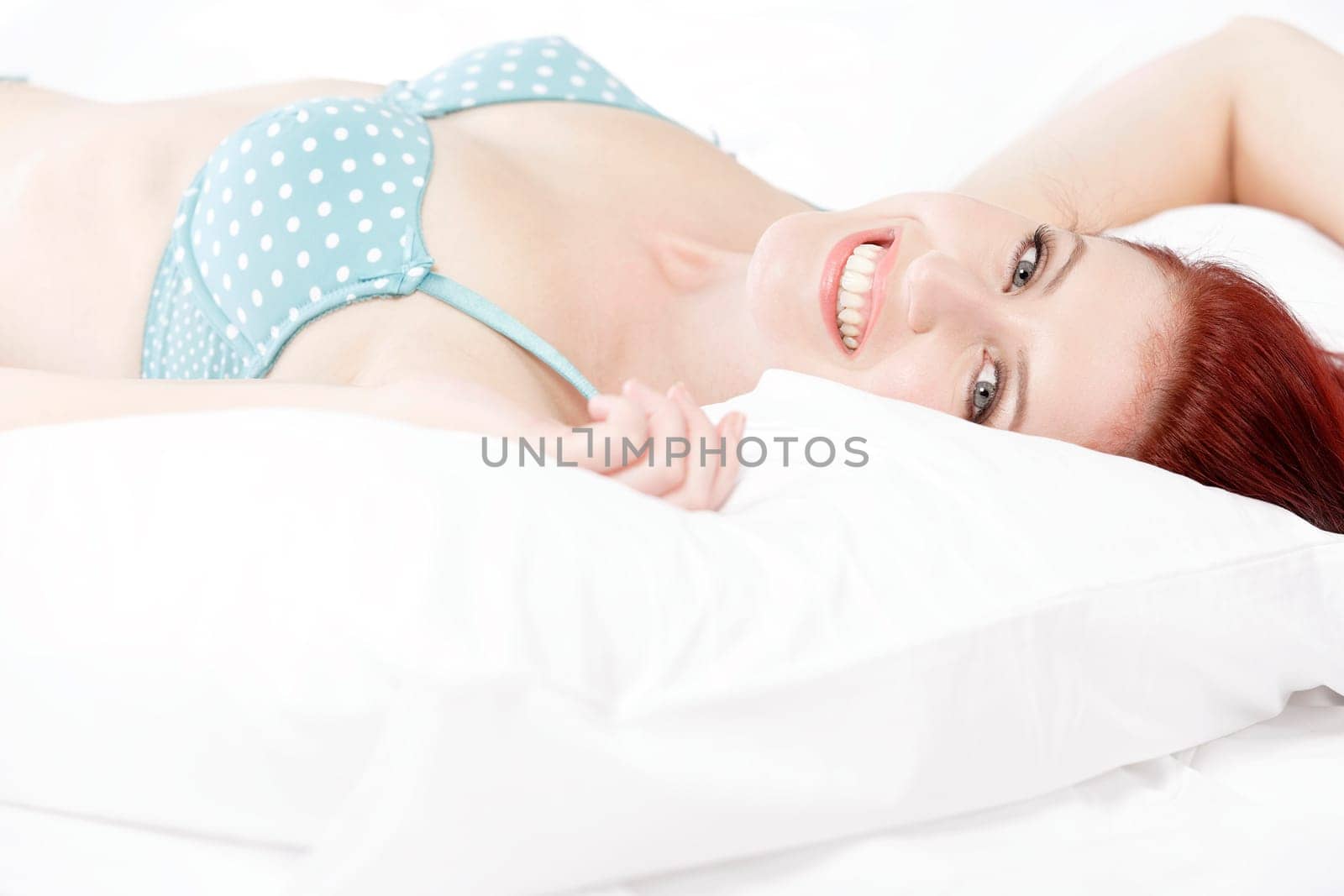Beautiful young woman resting on her bed at home in her underwear