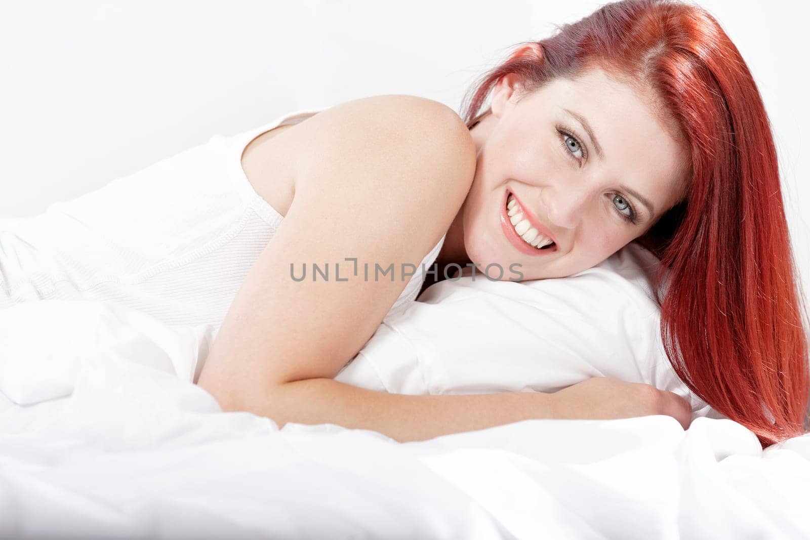Young woman lying on her white bed at home relaxing