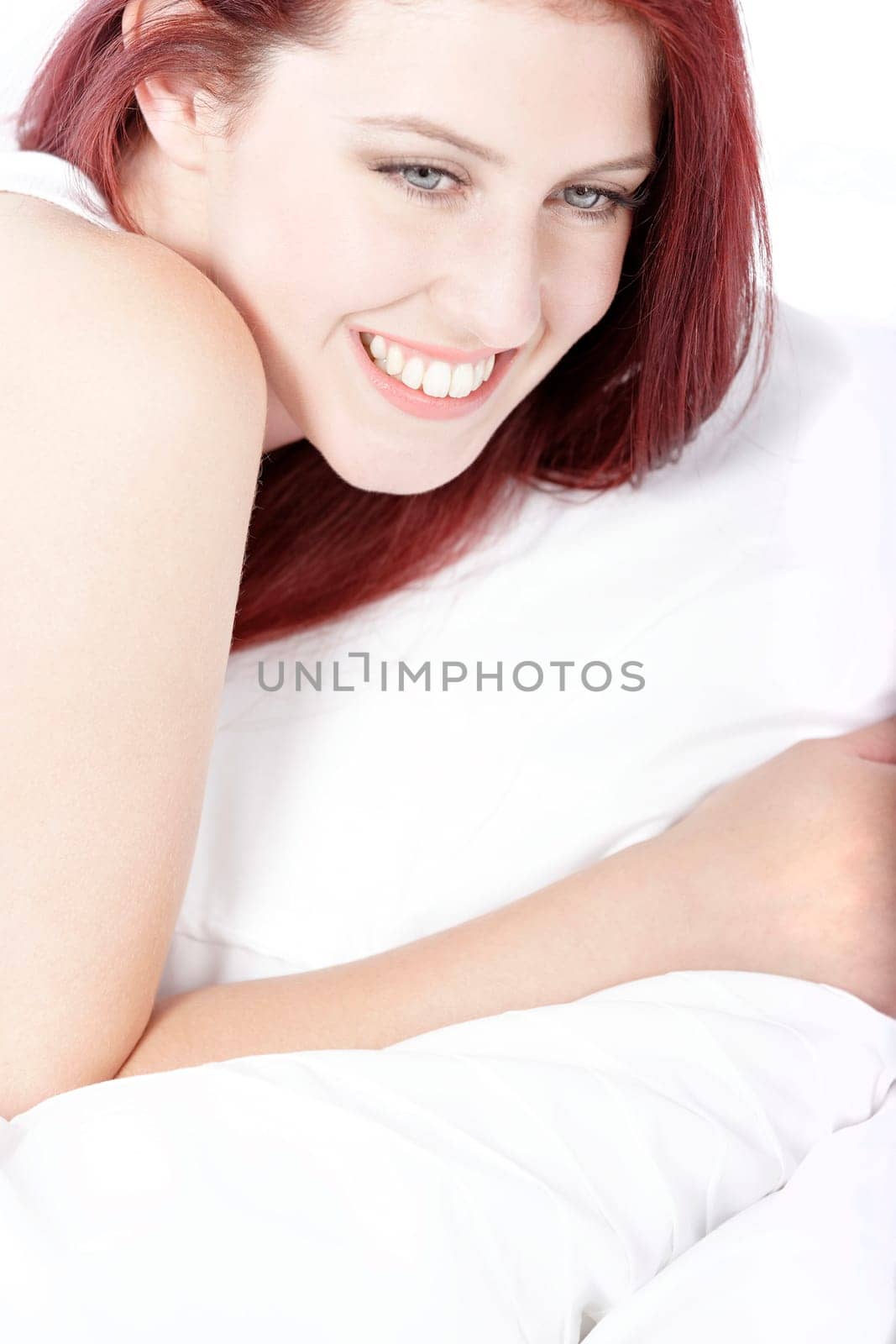 Young woman lying on her white bed at home relaxing
