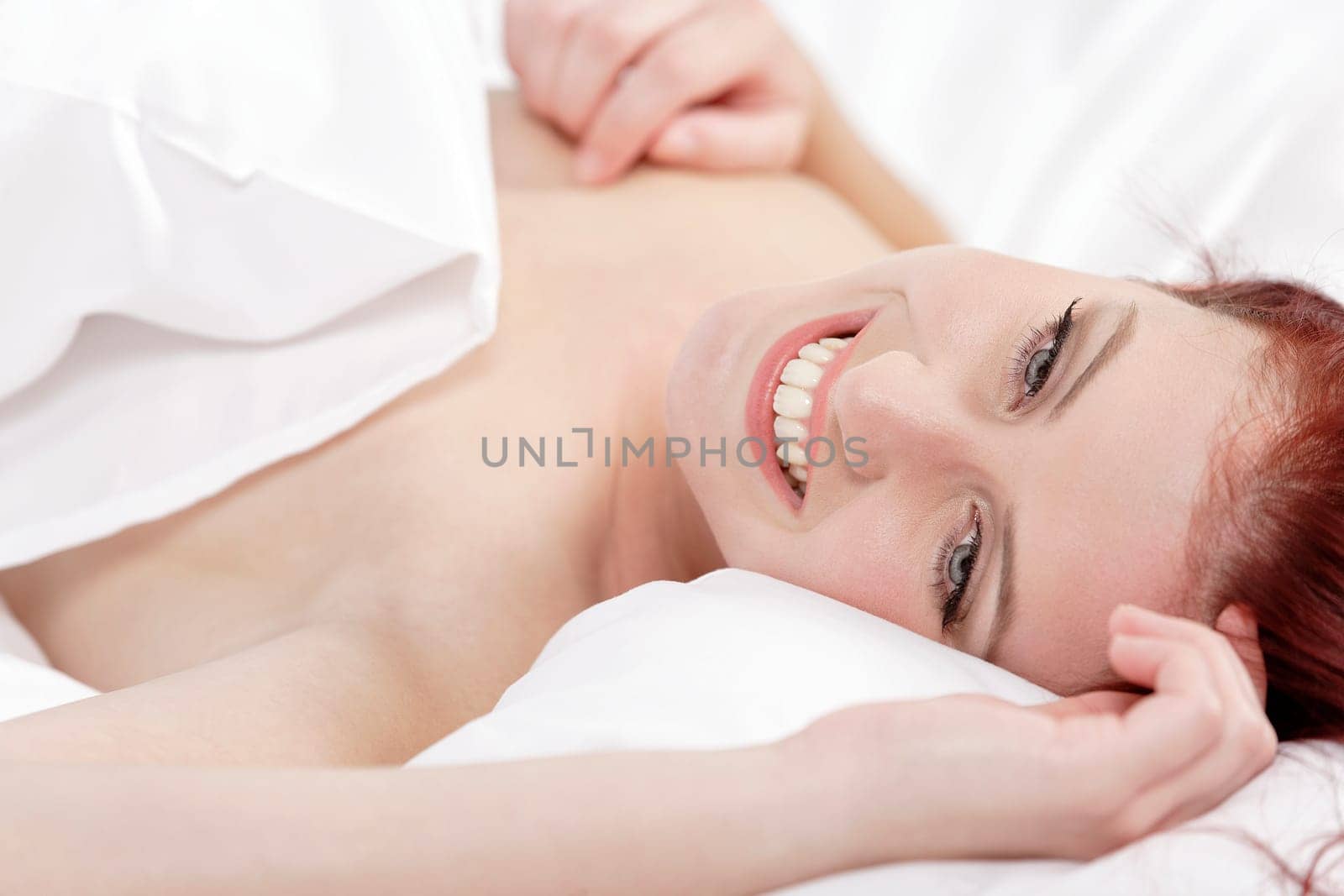 Attractive young woman holding a pillow on her bed at home