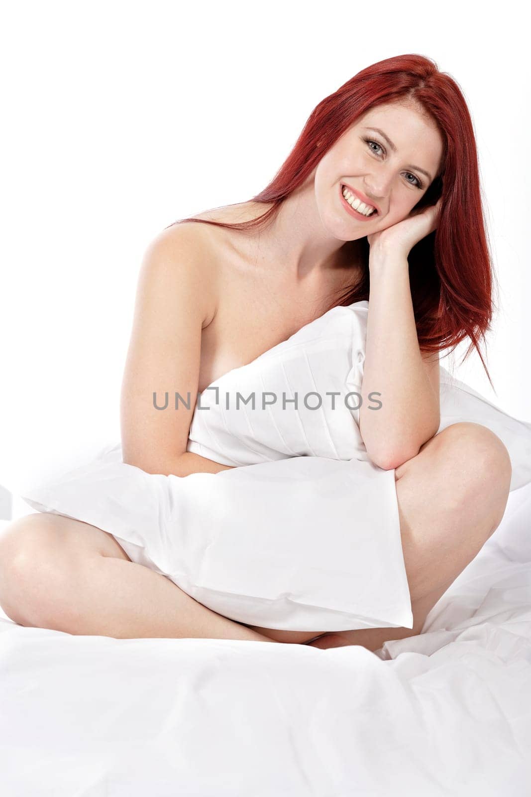 Attractive young woman holding a pillow on her bed at home