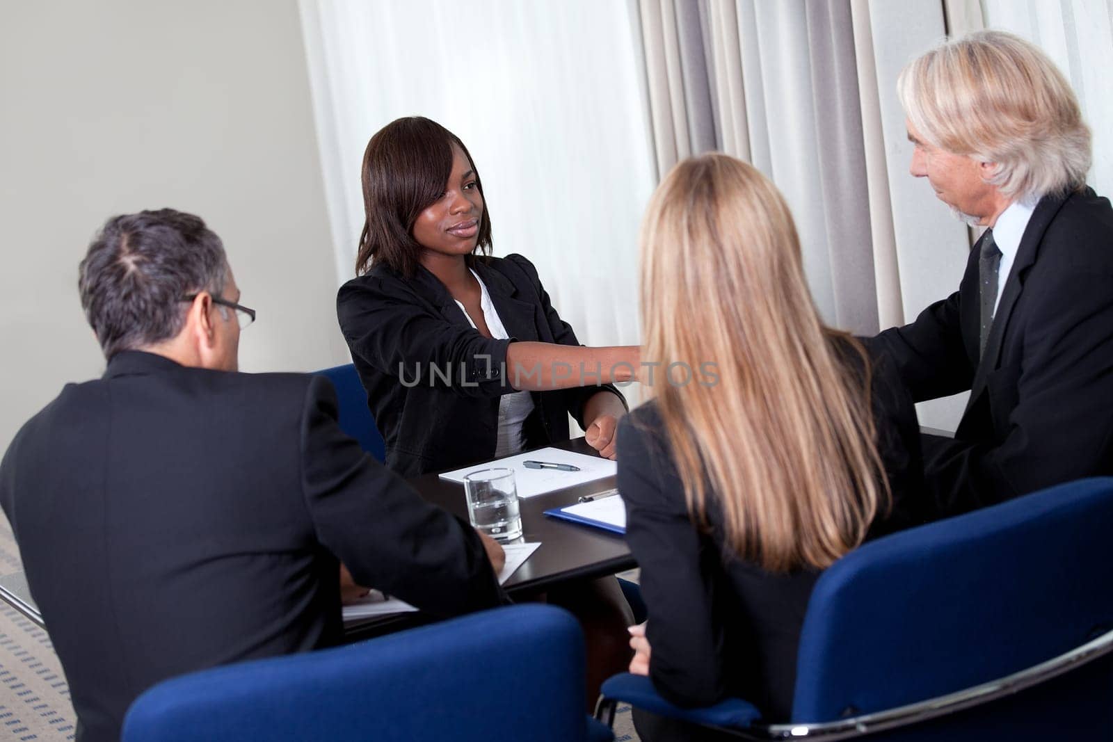 Mature group of business managers conducting job interview shaking hands with applicant at a table in meeting room