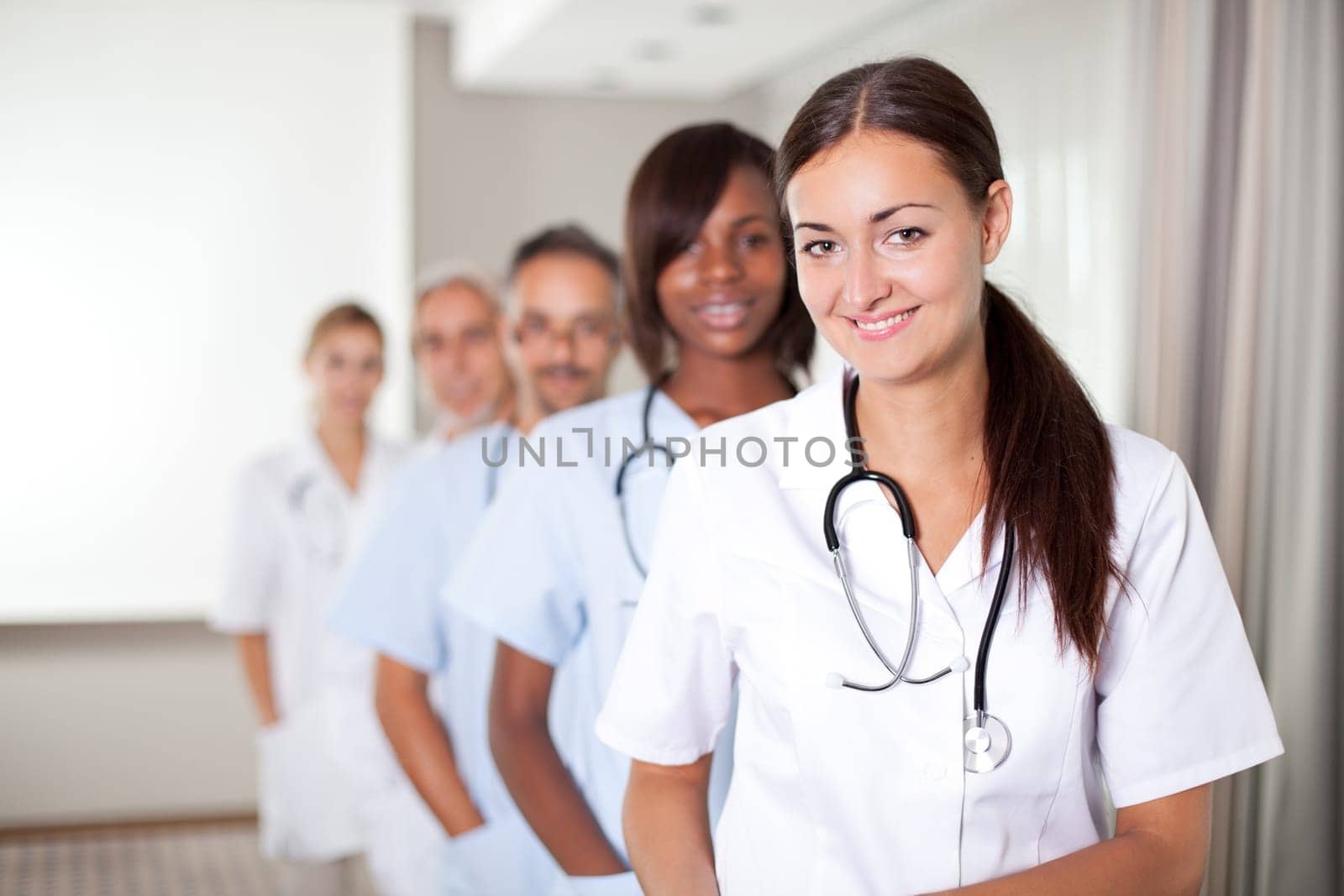 Mature young female doctor with group of happy successful colleagues