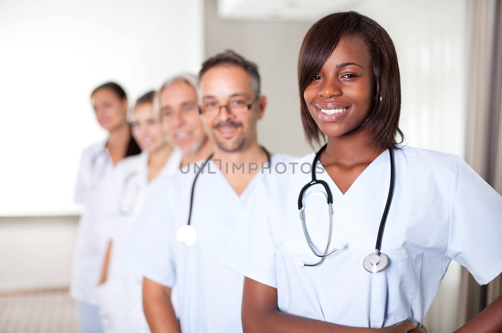 Multi-ethnic team of confident happy doctors standing in a row at the hospital