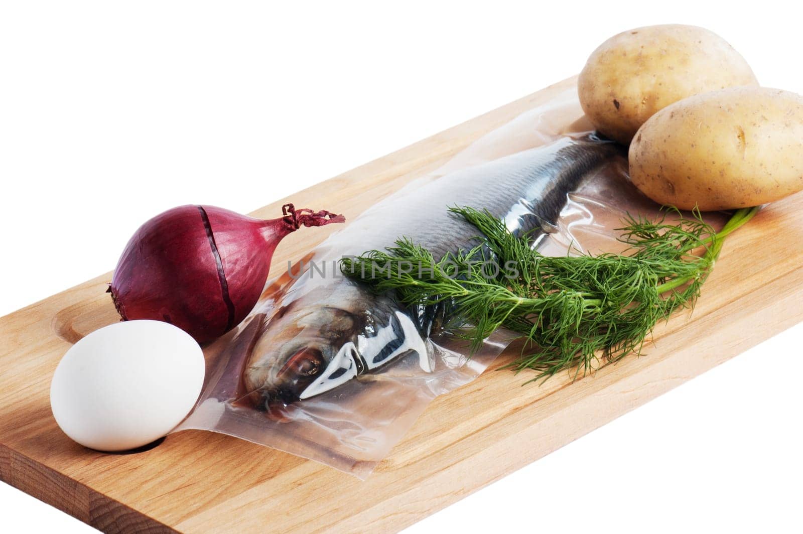 Vegetables and a salty herring on a kitchen board
