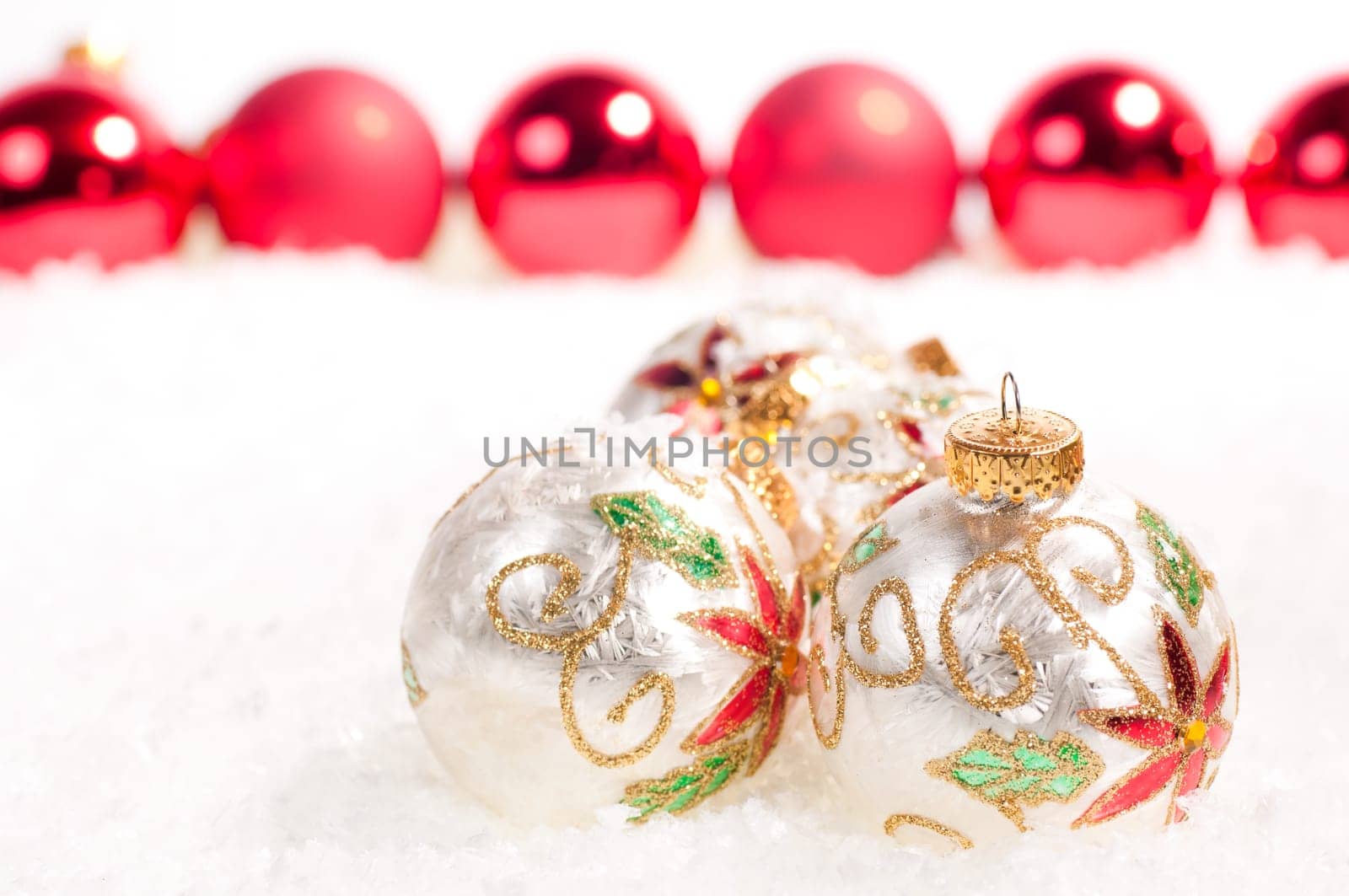 White glass baubles and a line of red baubles in the background on snow