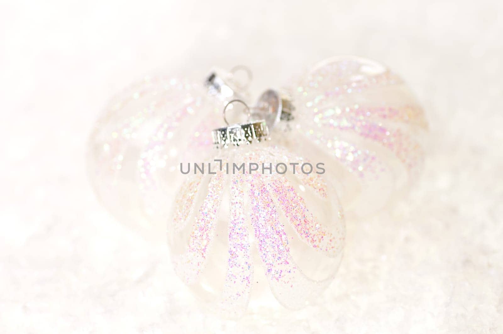 Three white glass Christmas baubles on snow